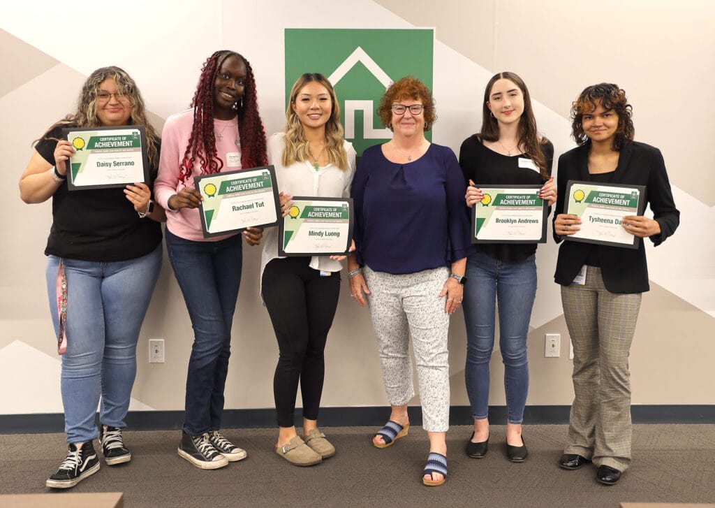 Group of female interns pose with certificates of achievement. 