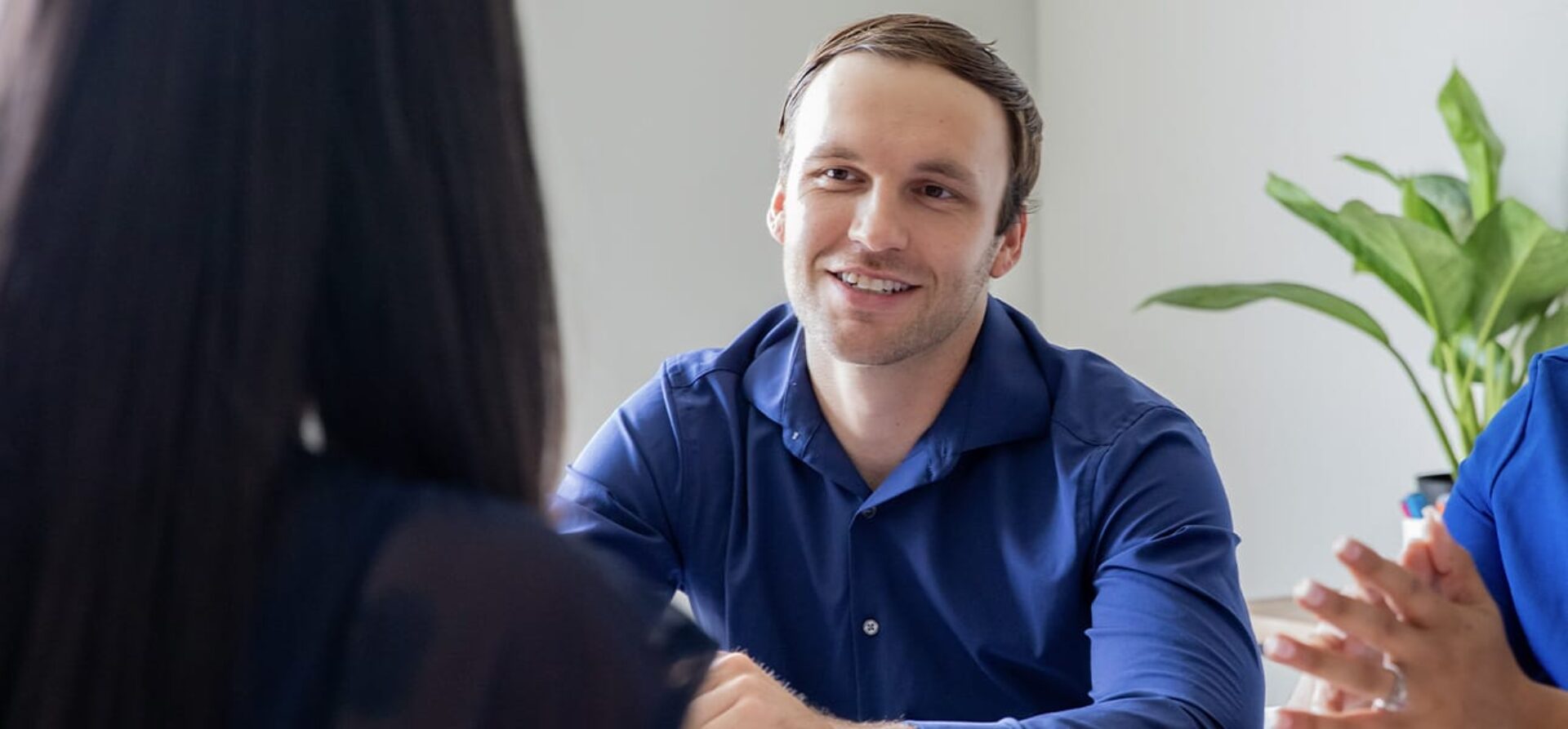 Man wearing a blue button-down shirt in a meeting with colleagues