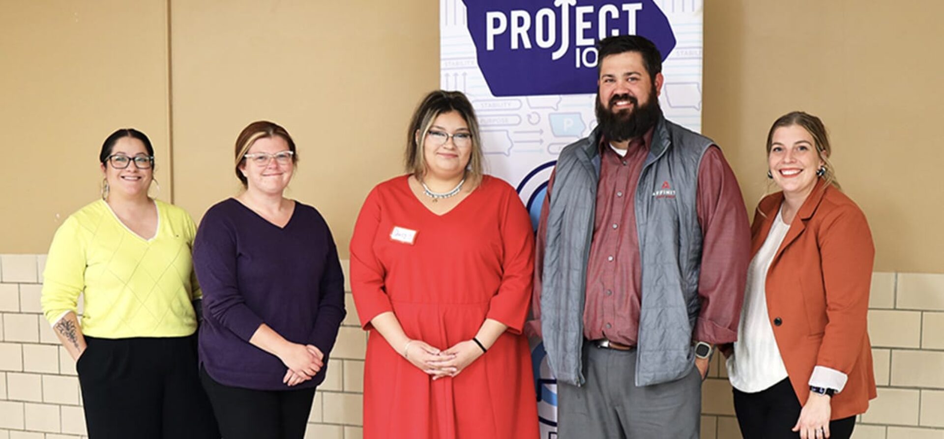Group of business people pose in front of vertical Project Iowa banner.