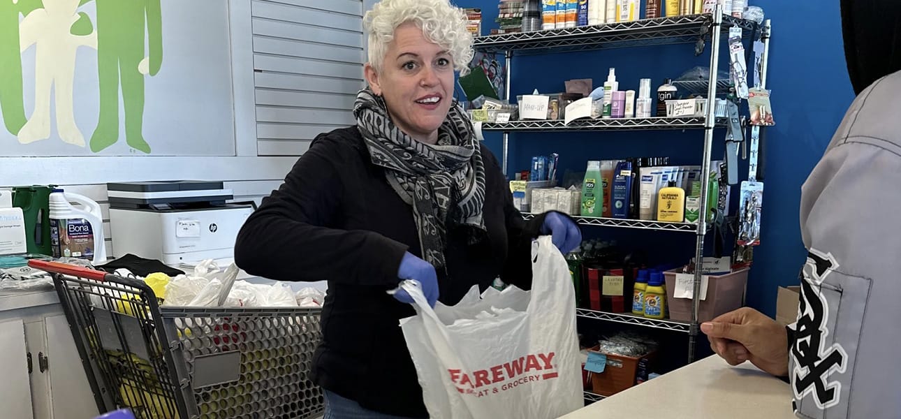 Woman puts items into a plastic grocery bag