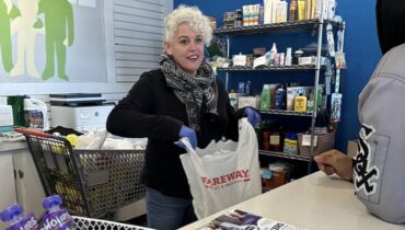 Woman puts items into a plastic grocery bag
