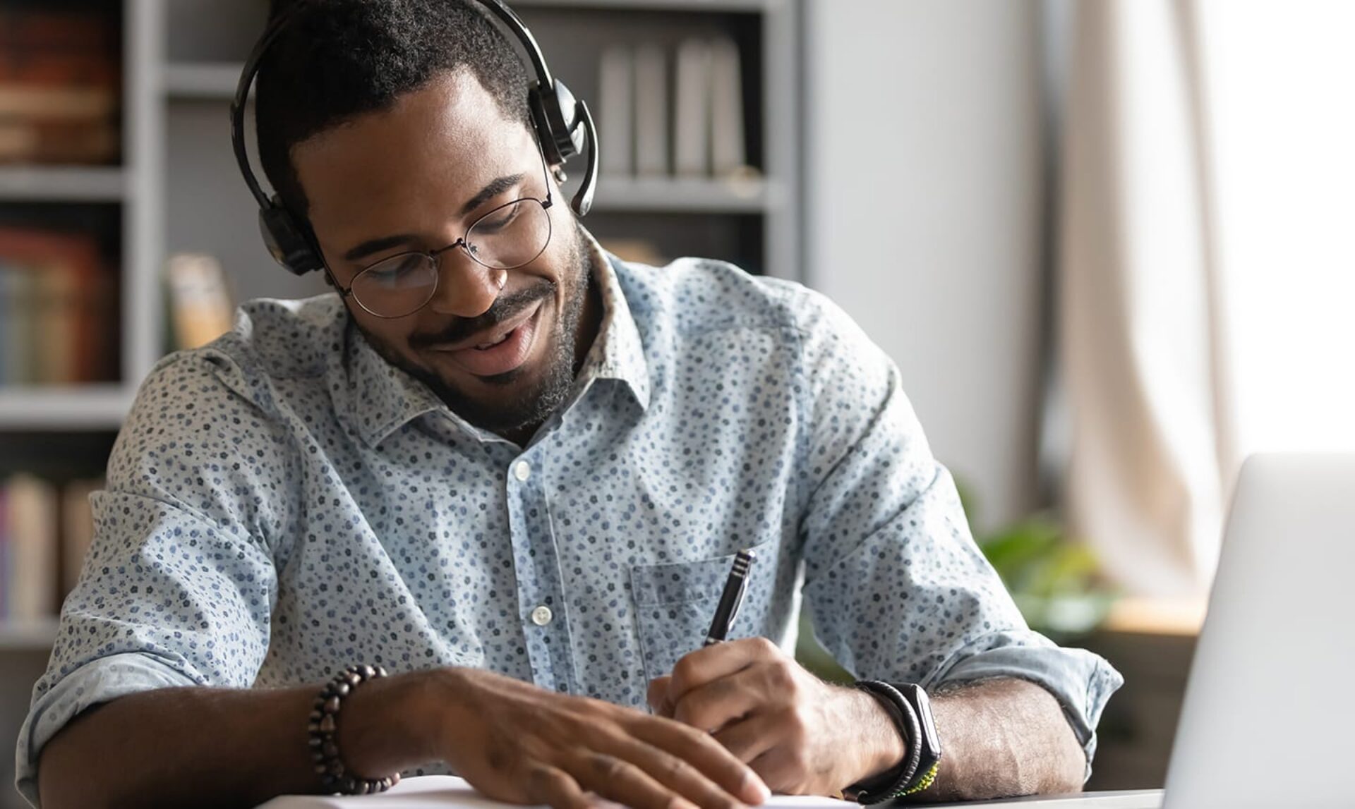 Smiling african male student professional wear headset elearning making notes